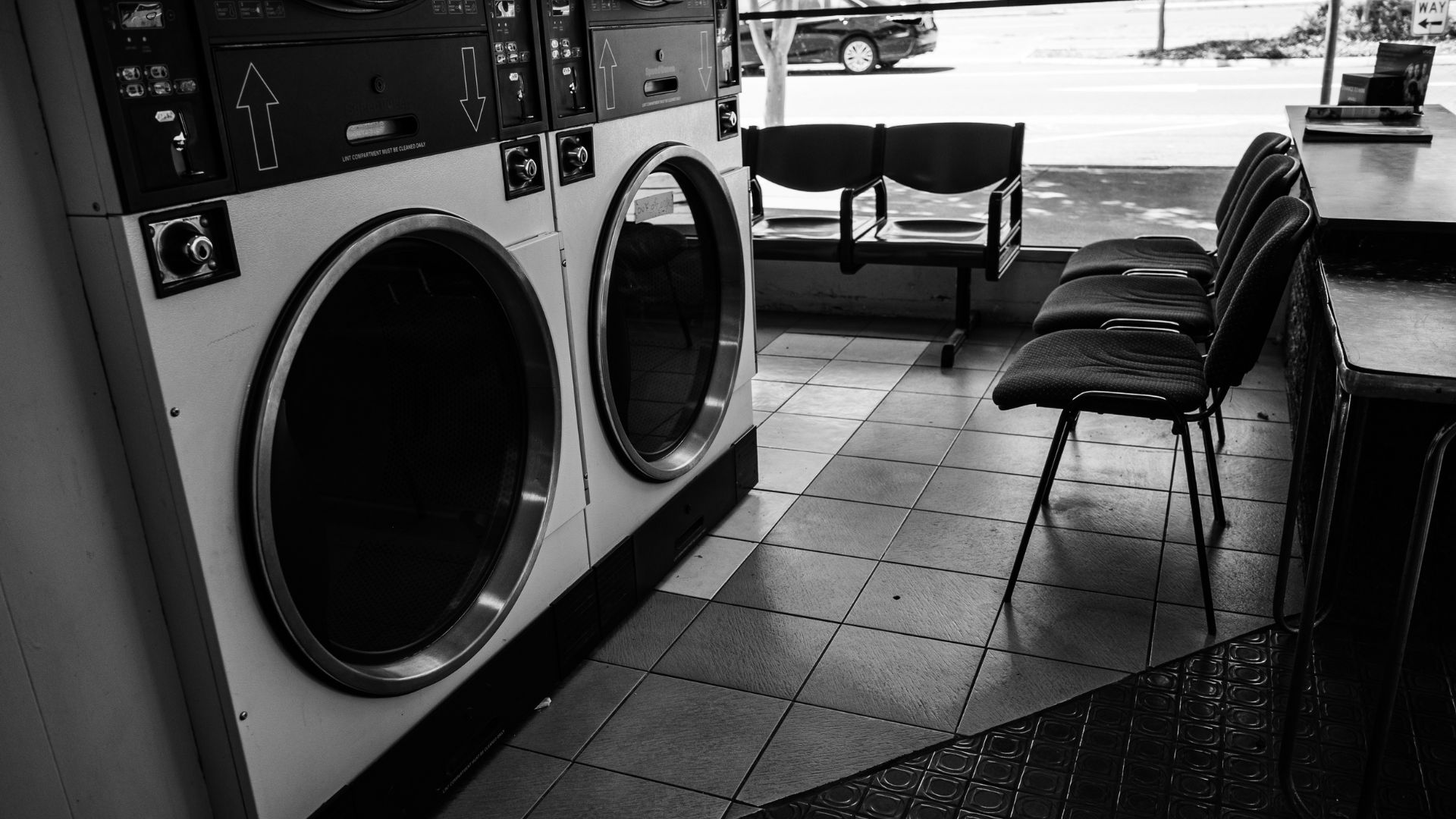 Empty laundromat with large industrial washing machines and waiting chairs