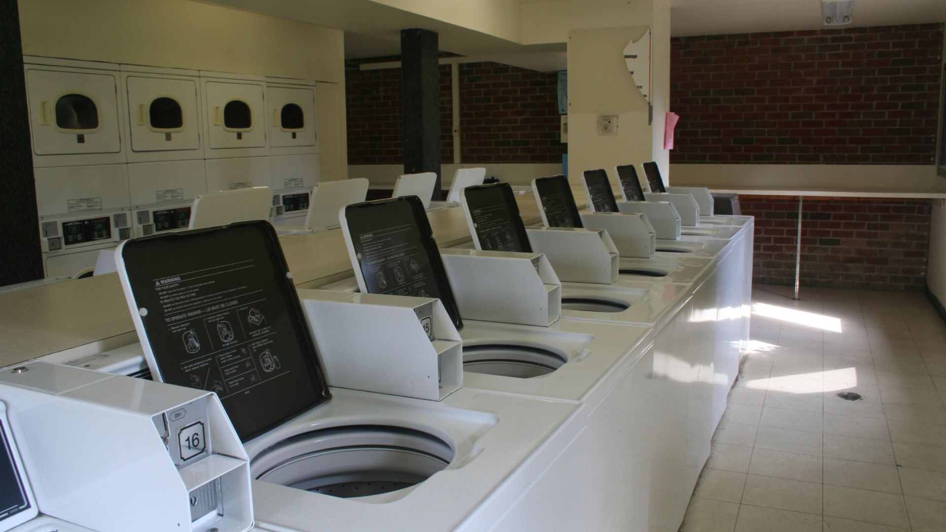 Empty laundromat with white washing machines and digital control panels
