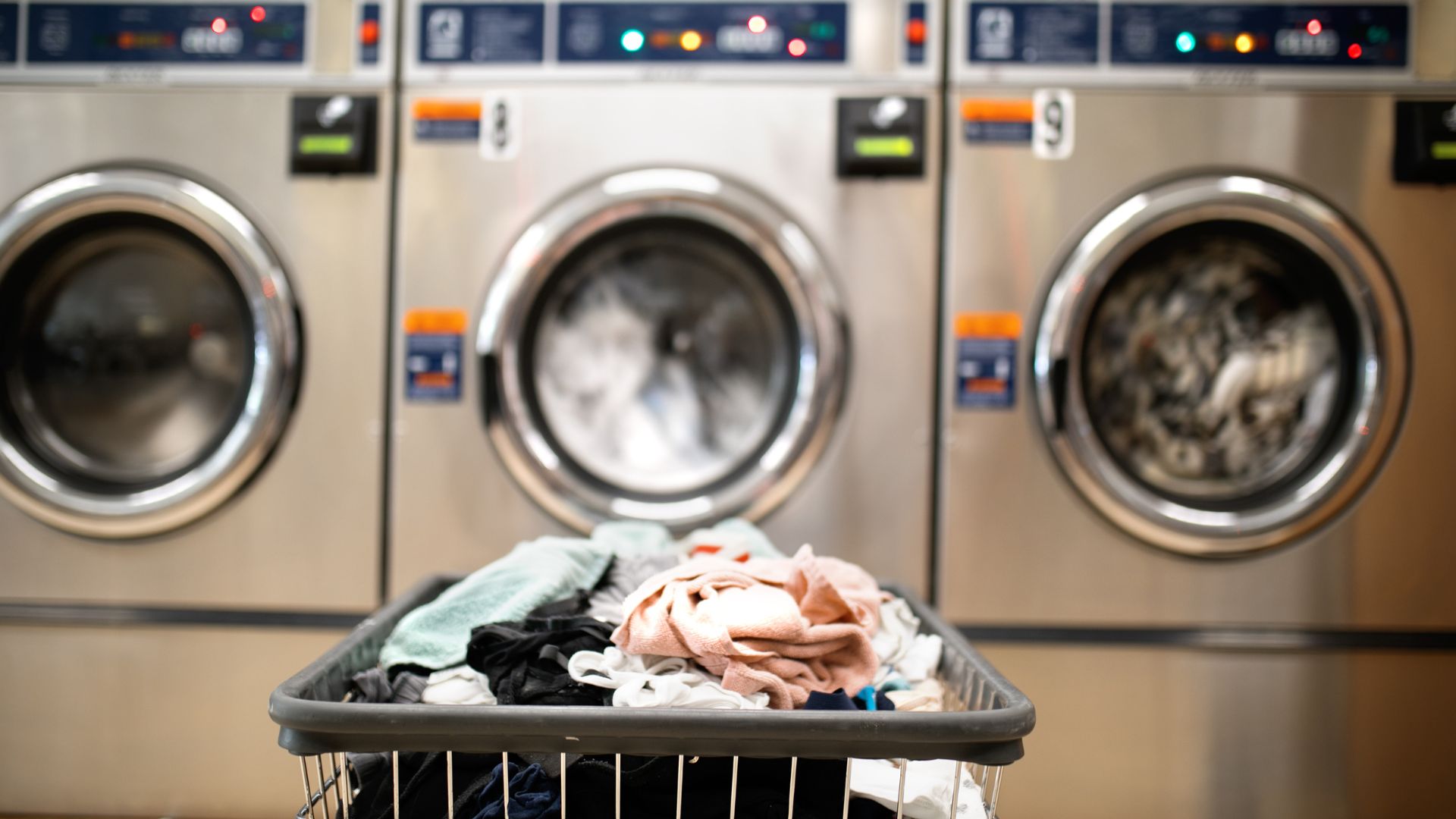 Laundry basket with clothes in front of industrial washing machines
