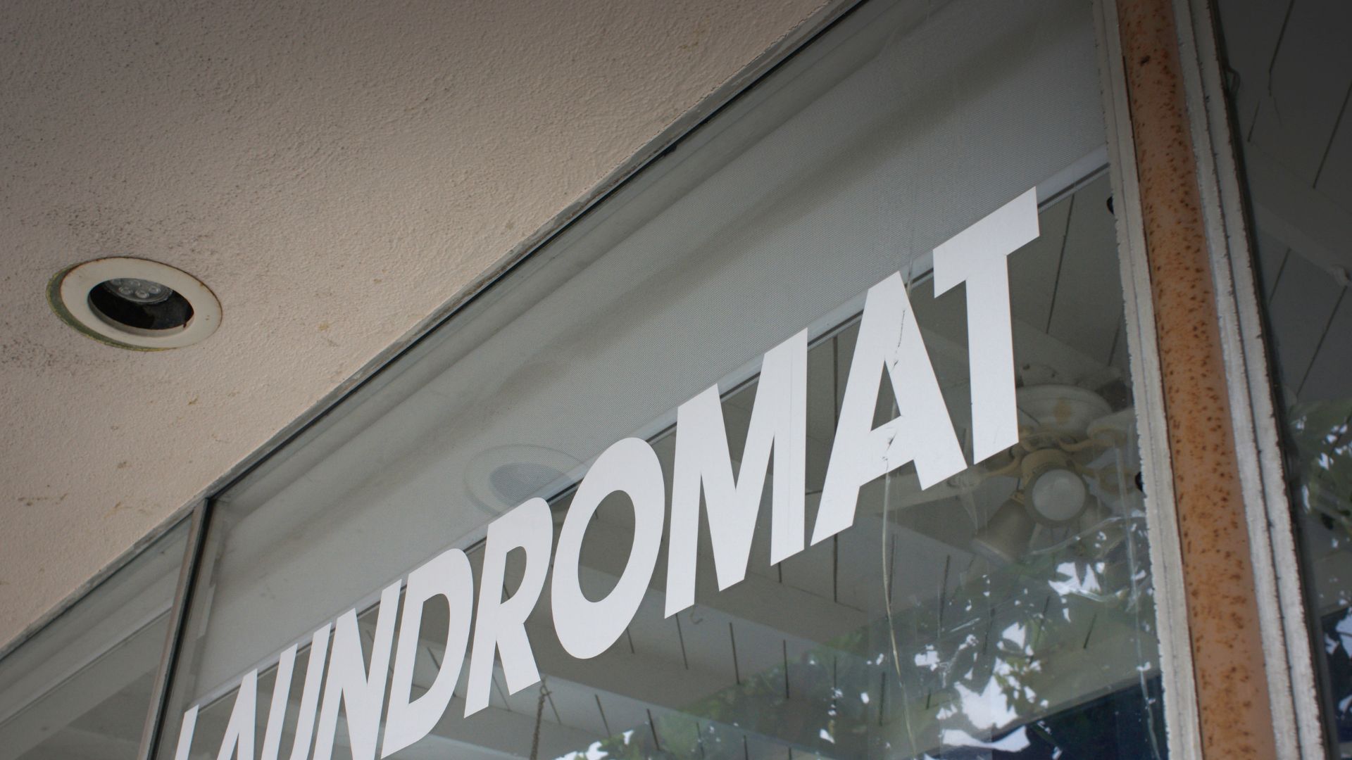Close-up of Laundromat sign on glass window with ceiling light