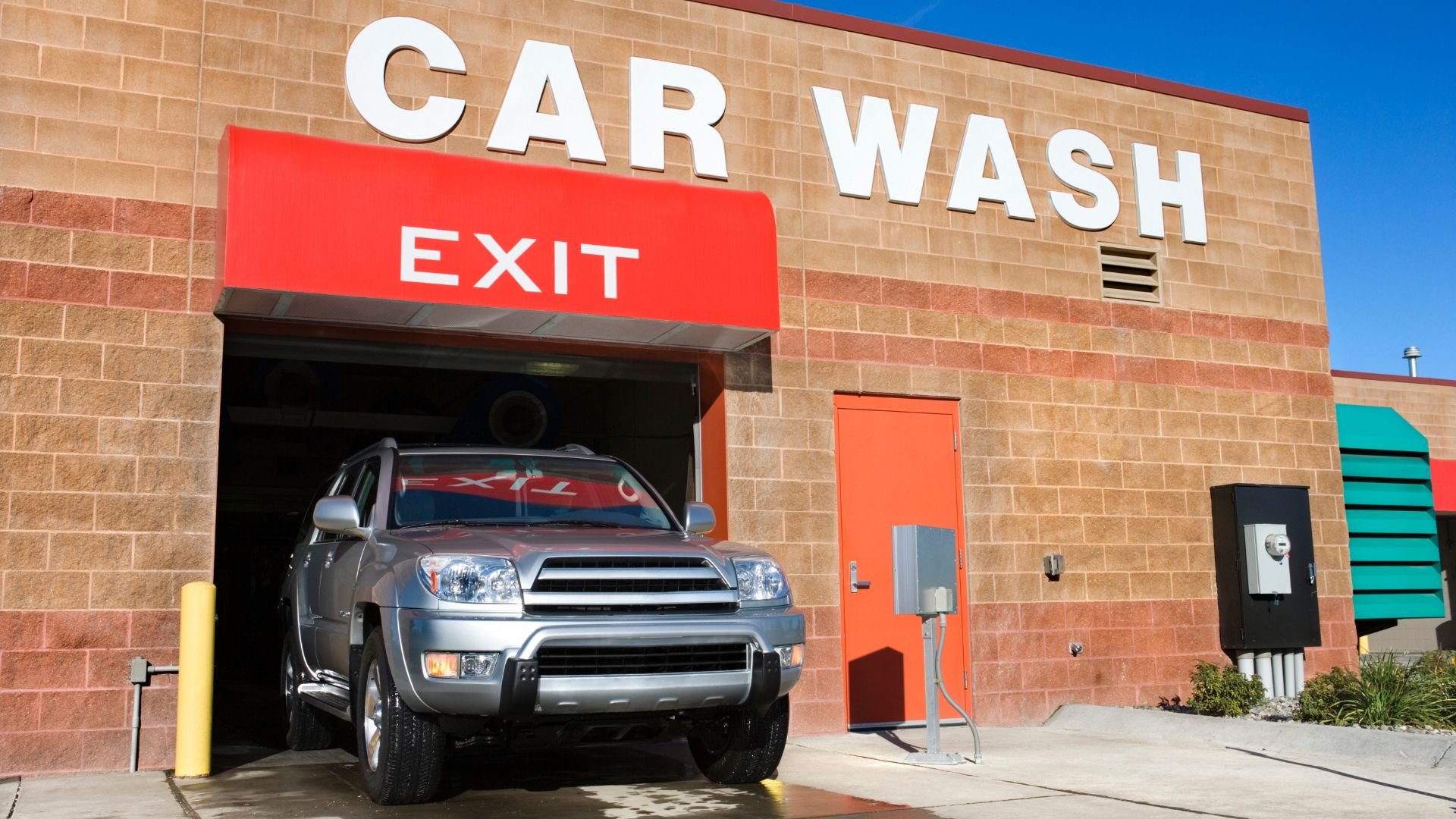 Silver SUV exiting a car wash through a red EXIT sign